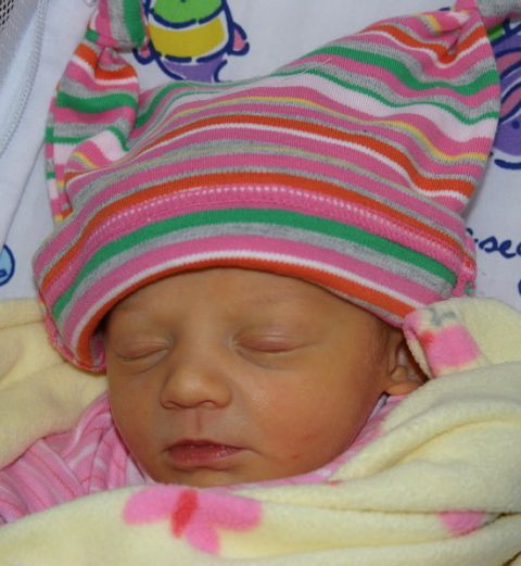 2003 Jeep TJ - A close-up of a sleeping newborn baby dressed in a colorful striped hat and wrapped in a soft yellow blanket.