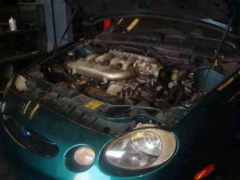 1997 Ford Taurus - The engine bay of a teal 1997 Ford Taurus is visible with the hood up.