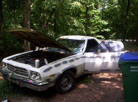 1973 Ford Ranchero - A white Ford Ranchero with its hood and door open sits in a wooded area, showing primer patches.