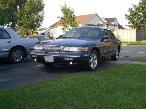 1985 Mercury Grand Marquis - Two sedans parked in a residential driveway on a sunny day.