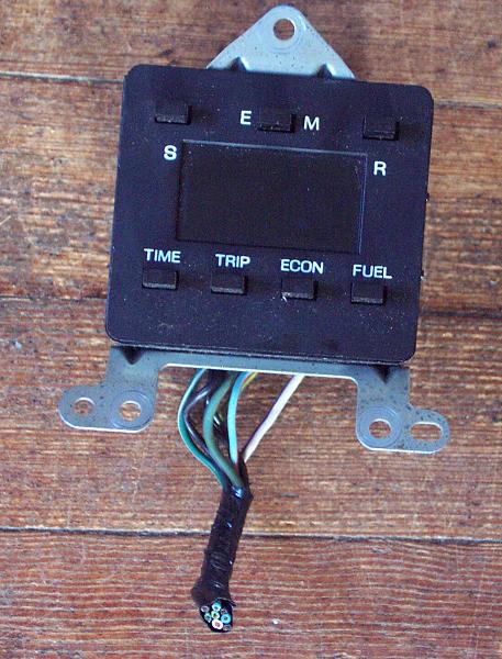 1985 Ford LTD Crown Victoria - A digital dashboard display unit with wires attached sits on a wooden surface.