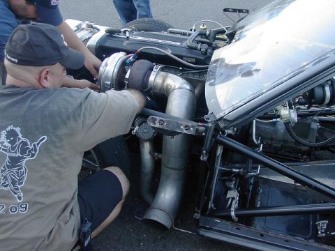 1990 Nissan Sentra - Mechanics work on a custom turbocharged engine, focusing on the turbocharger and exhaust system.