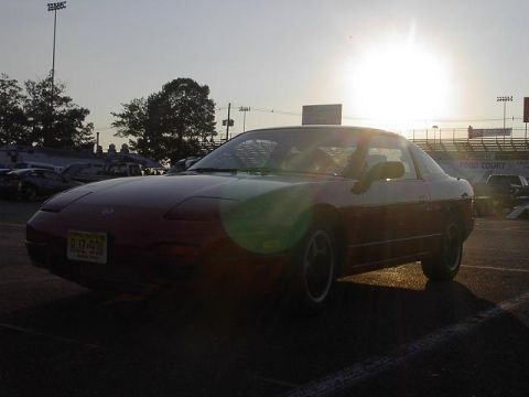 1990 Nissan Sentra - A red Nissan 240SX is parked in a lot as the sun sets behind it.
