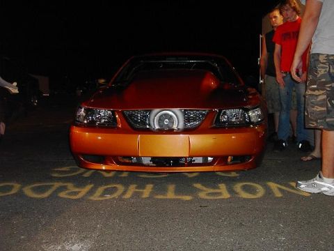 1990 Nissan Sentra - A modified orange sports car is parked on asphalt with yellow markings, showing its front grille with a turbocharger.