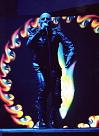1991 Ford Bronco - Performer in a black leather suit sings into a microphone with a fiery ring behind them on stage.