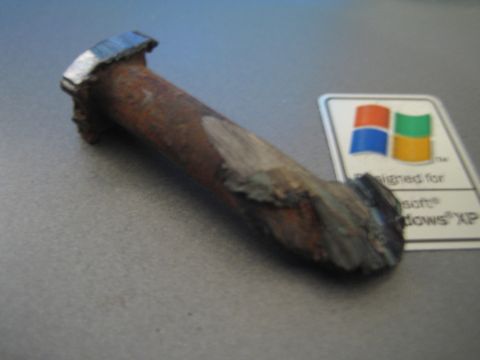 1990 Ford Bronco - severely rusted and broken metal bolt or stud lies on a gray laptop next to a Designed for Windows XP sticker.