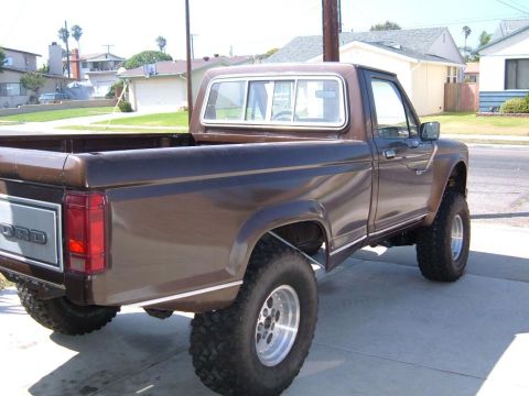 1985 Ford Ranger - This lifted Ford pickup truck is parked on a paved surface in a residential area.