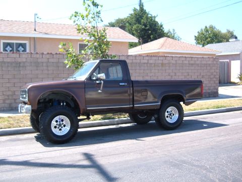1985 Ford Ranger - A lifted brown pickup truck is seen from the side, parked on a suburban street.