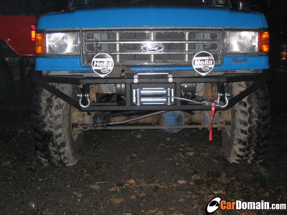 Blue Ford Bronco front end with Hella lights, tube bumper and winch at night