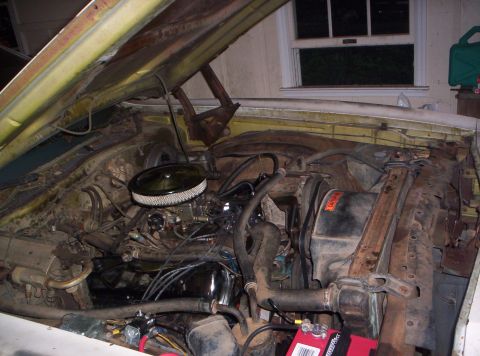 1973 Ford Ranchero - The engine bay of a vehicle, showing the carburetor, air filter, and various hoses and wires.