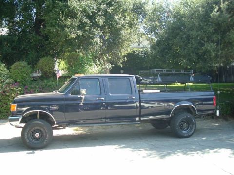 1979 Ford Bronco - Side view of a dark blue crew cab pickup truck equipped with a roof rack.