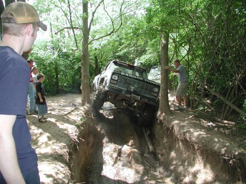1977 Ford F-150 - A modified pickup truck navigates a challenging off-road obstacle with spectators observing the action.