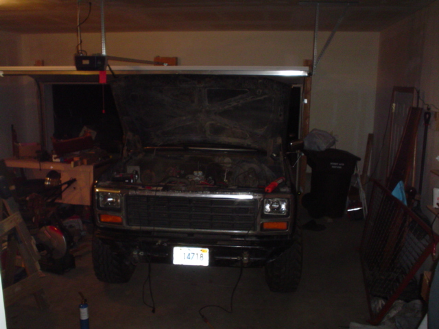 Square-body Ford Bronco with hood open parked inside a dim garage, plate reading 14718