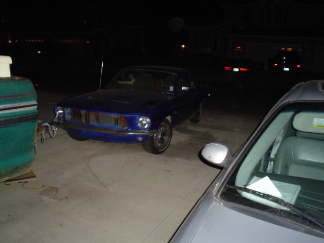 Blue Mustang fastback coupe parked at night, front three-quarter view