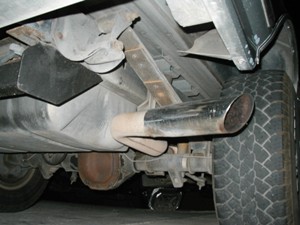 1989 Ford Bronco - Close-up view of the underside of a vehicle, highlighting the exhaust system and a tire. The Supermotors.net logo is visible.