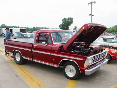 1972 Ford Ranchero - A red pickup truck is displayed with its hood open, alongside other vehicles at an outdoor event.
