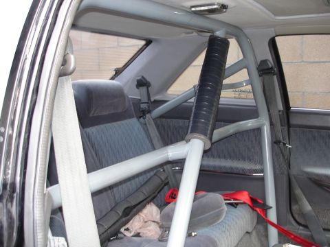 1989 Mazda MX-6 - Interior view of a car's roll cage and seats, with a visible red seatbelt.