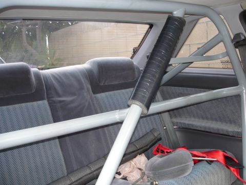 1989 Mazda MX-6 - The interior of a car is shown, a prominent roll cage and grey patterned upholstery on the seats.