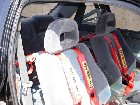 1989 Mazda MX-6 - The interior of a car is shown, racing seats and prominent red harnesses.