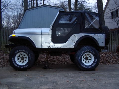 1978 Jeep CJ5 - Side view of a silver 1978 Jeep CJ5, a black soft top and off-road tires.
