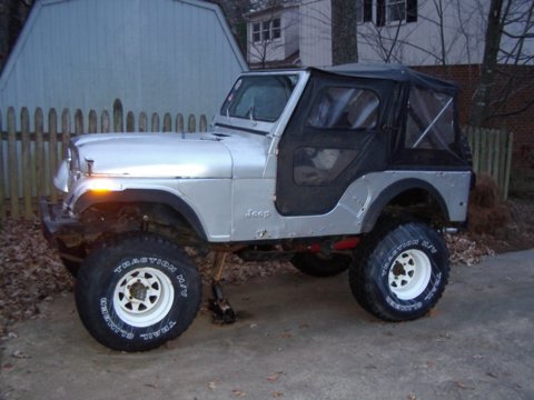1978 Jeep CJ5 - Silver 1978 Jeep CJ5 with a black soft top and lifted suspension is parked outside.