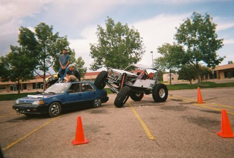 1972 Ford Ranchero - An off-road buggy is positioned next to a sedan with people sitting on its roof.