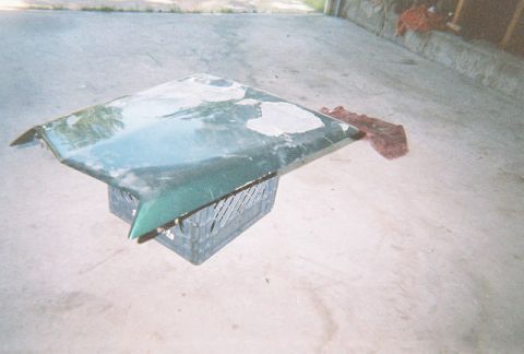 1972 Ford Ranchero - A green car hood, showing signs of wear and repair, is placed on a crate outdoors.