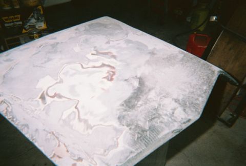 1972 Ford Ranchero - A car hood is shown with extensive body filler and primer, indicating repair or preparation for painting.