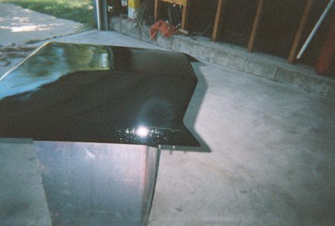 1972 Ford Ranchero - A car hood sits on a stand in a garage, reflecting light from above.