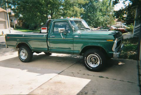1972 Ford Ranchero - A green pickup truck with a 'for sale' sign is parked in a driveway on a sunny day.