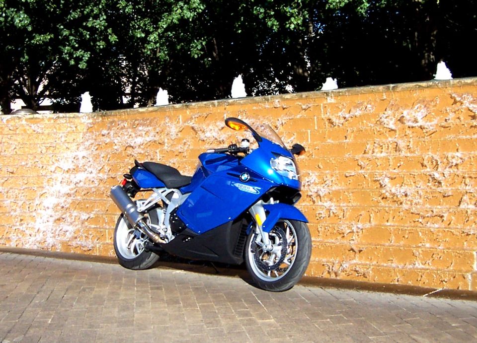 Blue 2005 BMW R1200CA ABS motorcycle parked on brick pavement next to a textured orange wall