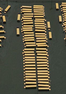 1972 Ford Ranchero - Numerous yellow cylindrical objects are neatly arranged in parallel rows on a dark, reflective surface, likely water.