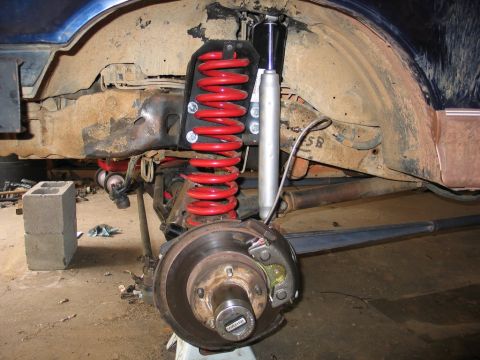 1995 Ford Bronco - Close-up view of a vehicle's front suspension system, bright red coil springs and a silver shock absorber.