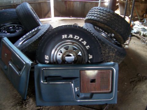1983 Ford Bronco - Interior car doors and radial tires are piled up, suggesting parts for a vehicle restoration.