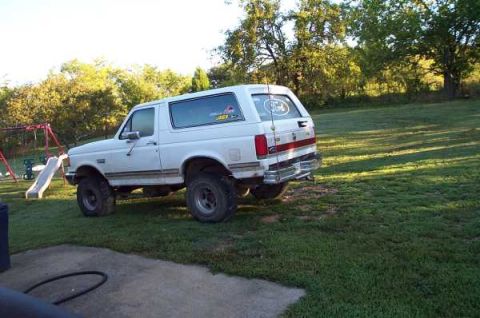 1988 Ford Bronco - White 1988 Ford Bronco seen from the rear quarter angle in a backyard setting.