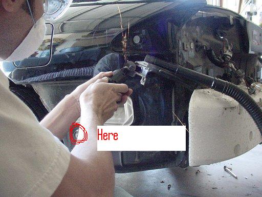 Person grinding on car fender, sparks flying. Part of car interior visible