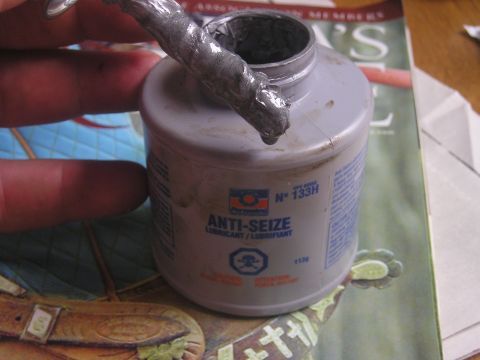 1984 Ford Bronco - Container of anti-seize lubricant with a hand holding a tool covered in the substance.