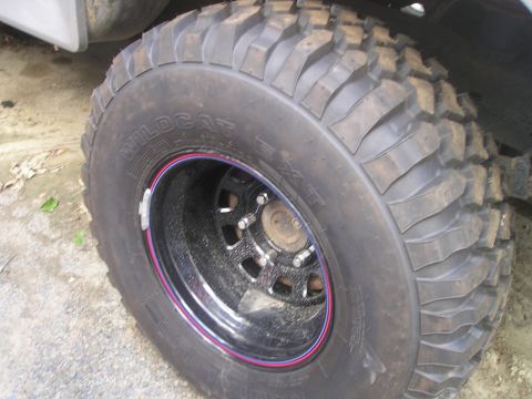 1984 Ford Bronco - Close-up of a vehicle's tire and wheel assembly, showing off-road tread and custom rim details.