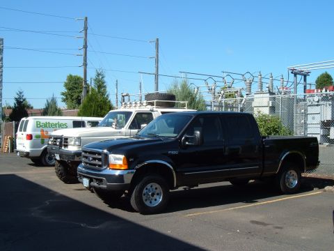 2000 Ford F-250 - A black 2000 Ford F-250 Super Duty truck is parked next to other vehicles in a lot.