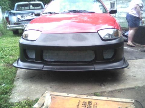 2005 Chevrolet Cavalier - Front bumper and grille of a red car, with a pickup truck in the background.