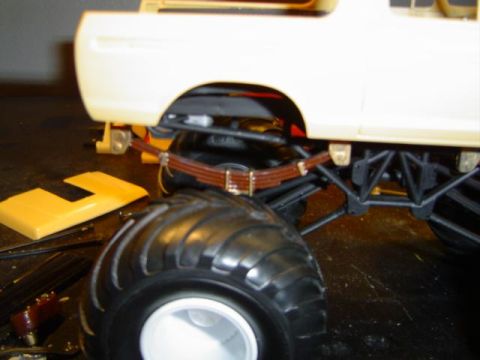 1979 Ford Bronco - Close-up view of a model truck's suspension and oversized tire, with unassembled parts nearby.