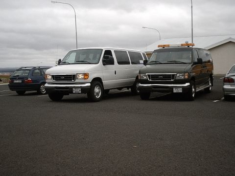 1996 Ford Bronco - Two vans and a wagon are parked in a lot under an overcast sky.