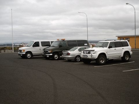 1996 Ford Bronco - Several vehicles are parked in an overcast lot, including a white SUV.
