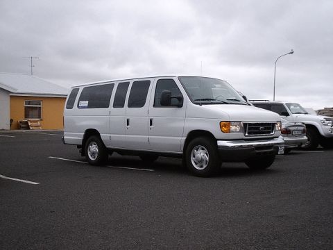 1996 Ford Bronco - A white van is parked in a lot with other vehicles under an overcast sky.