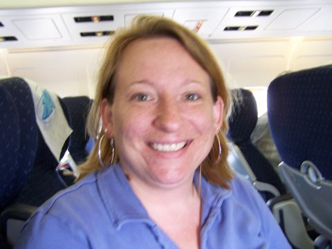 1979 Ford F-150 - A woman smiles while seated in an airplane, with rows of seats visible behind her.
