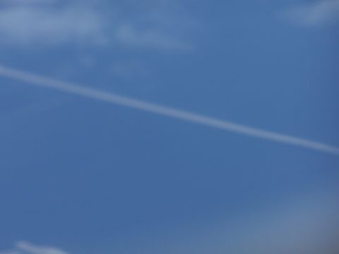 1979 Ford F-150 - A contrail is visible against a bright blue sky with scattered clouds.