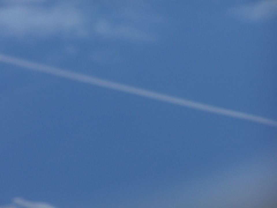 Contrail stretches across a clear blue sky