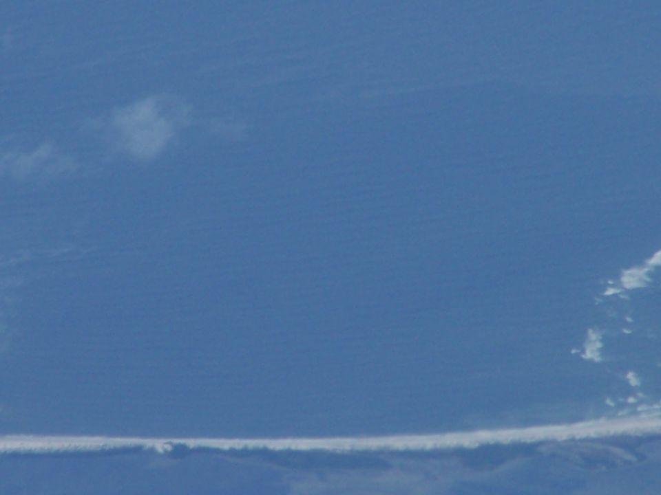 Blue sky with a long, thin cloud formation near the bottom and a few smaller clouds higher up