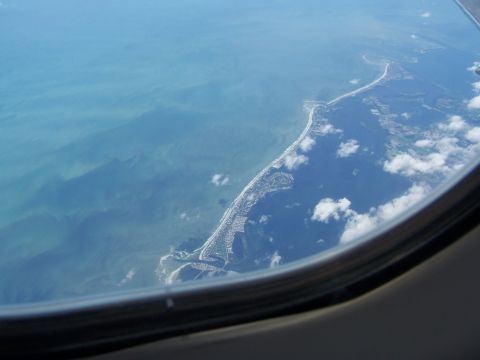 1979 Ford F-150 - View of a coastal community and the ocean from an airplane window, showing the shoreline and scattered clouds.