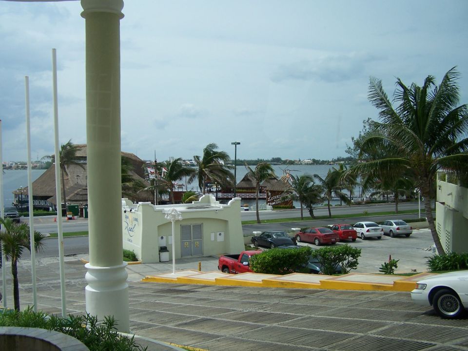 Red pickup truck parked in a lot with a body of water and palm trees in the background